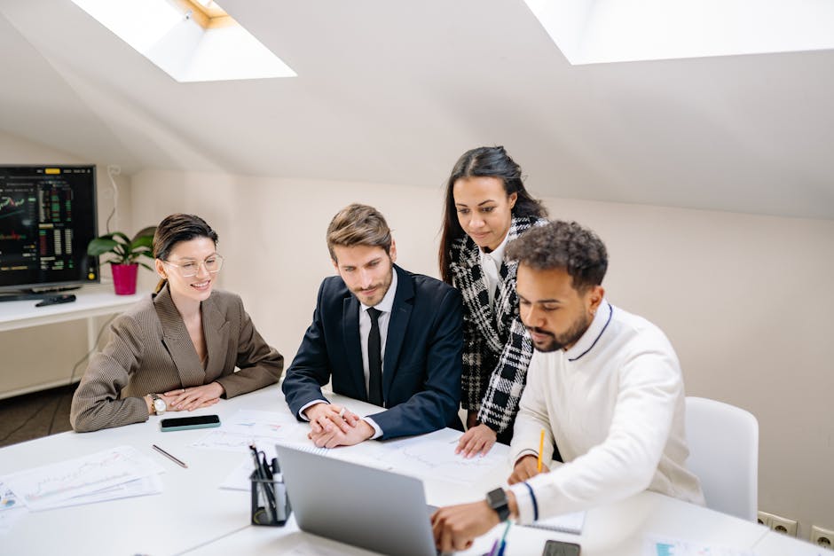 A diverse team of professionals collaborating and discussing work in a modern office setting.