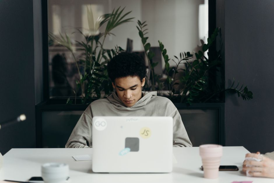 Focused young professional working on a laptop in a modern office environment.