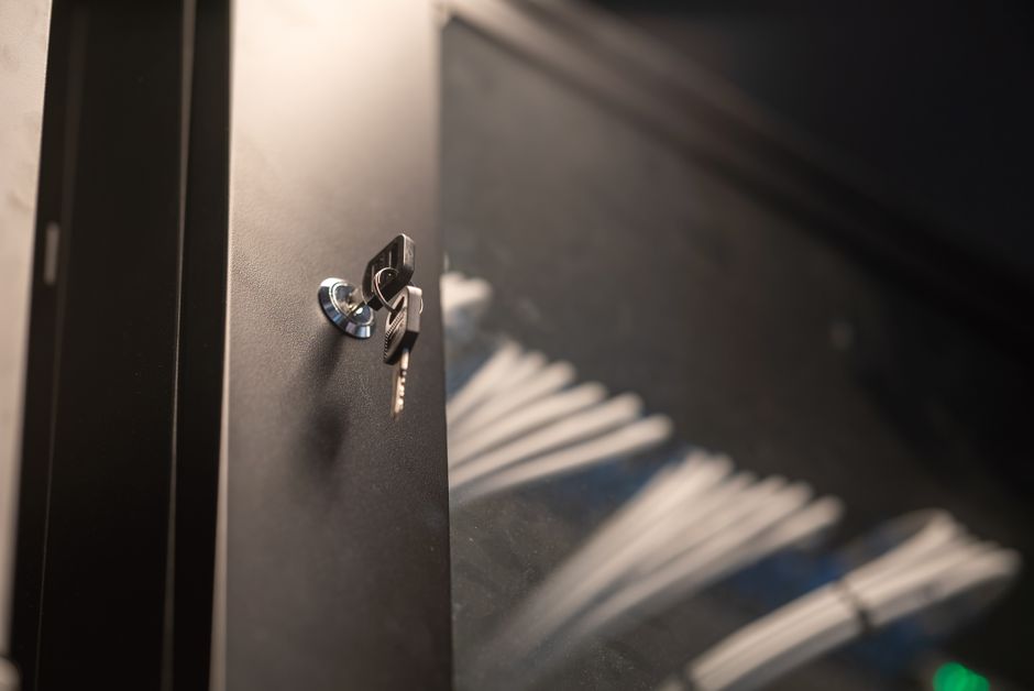 Detailed view of a key inserted into a modern lock on a metal cabinet door.