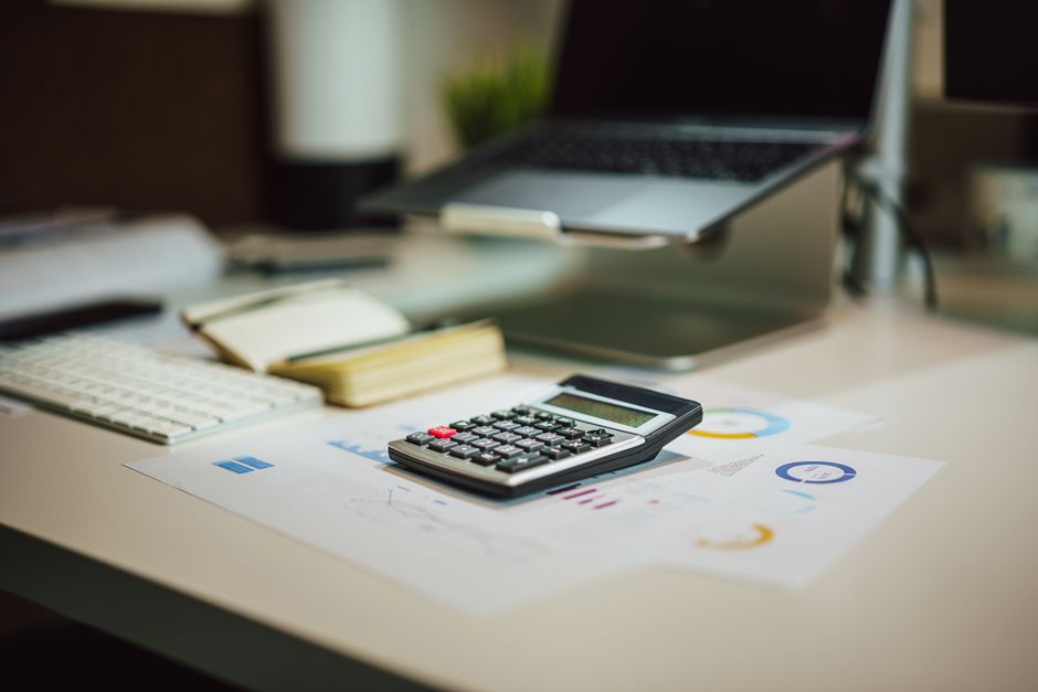 A modern workspace with a laptop, calculator, and documents on a desk, perfect for finance tasks.