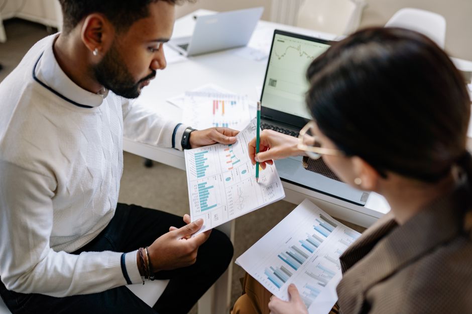 Two professionals reviewing data and graphs in a modern office setting for analysis.