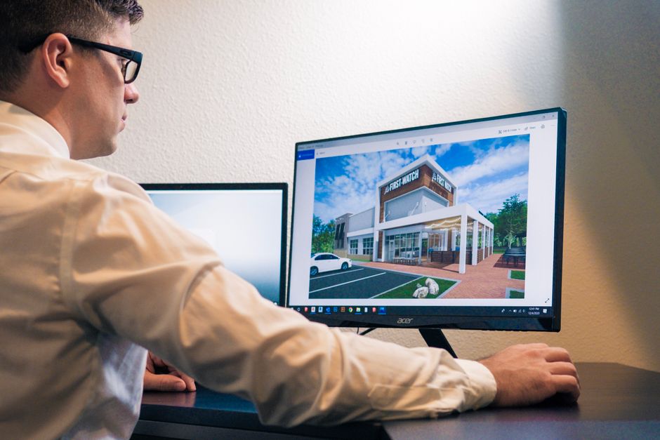 Architect evaluating a building design on a computer screen in an office setting.